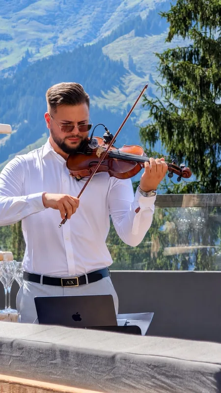 Rauf spielt Violine auf einer Terrasse vor Bergpanorama
